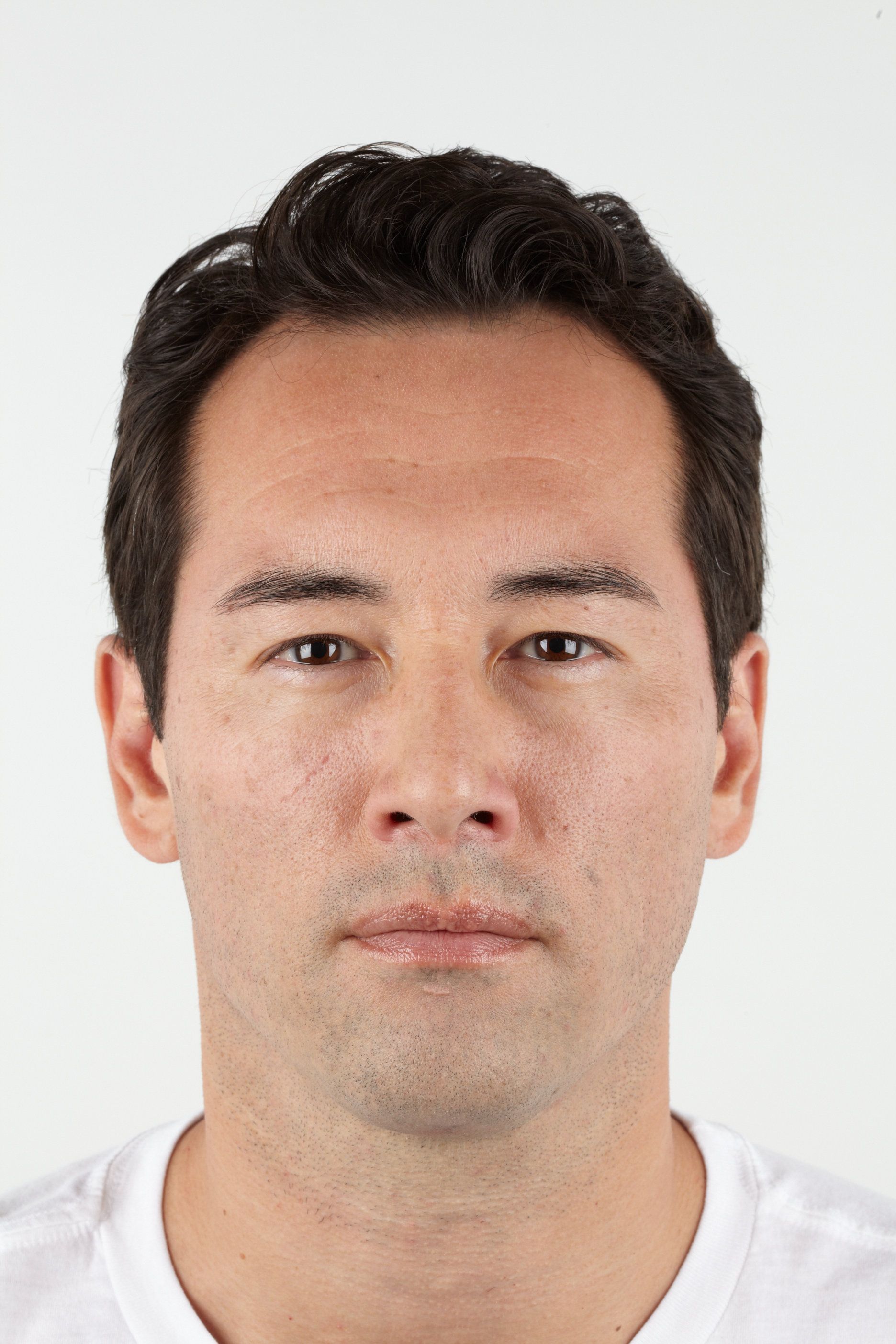 Man with dark hair and skin, neutral expression, wearing a white shirt against a white background.