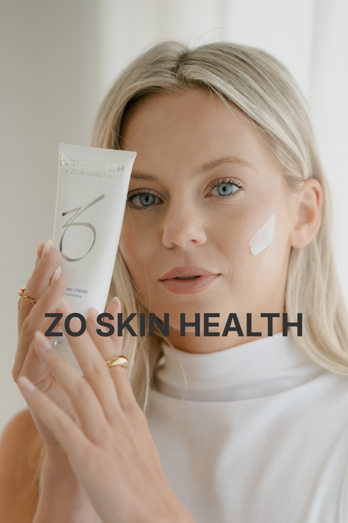 A person squeezing a tube of ZO Skin Health cream. The white cream is dispensed.