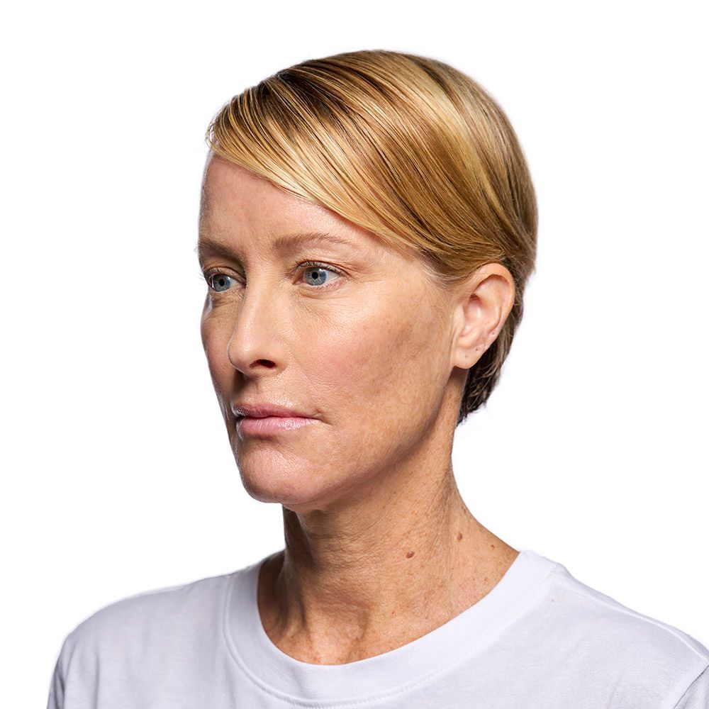 Woman with blonde hair looking to the side wearing a white shirt.