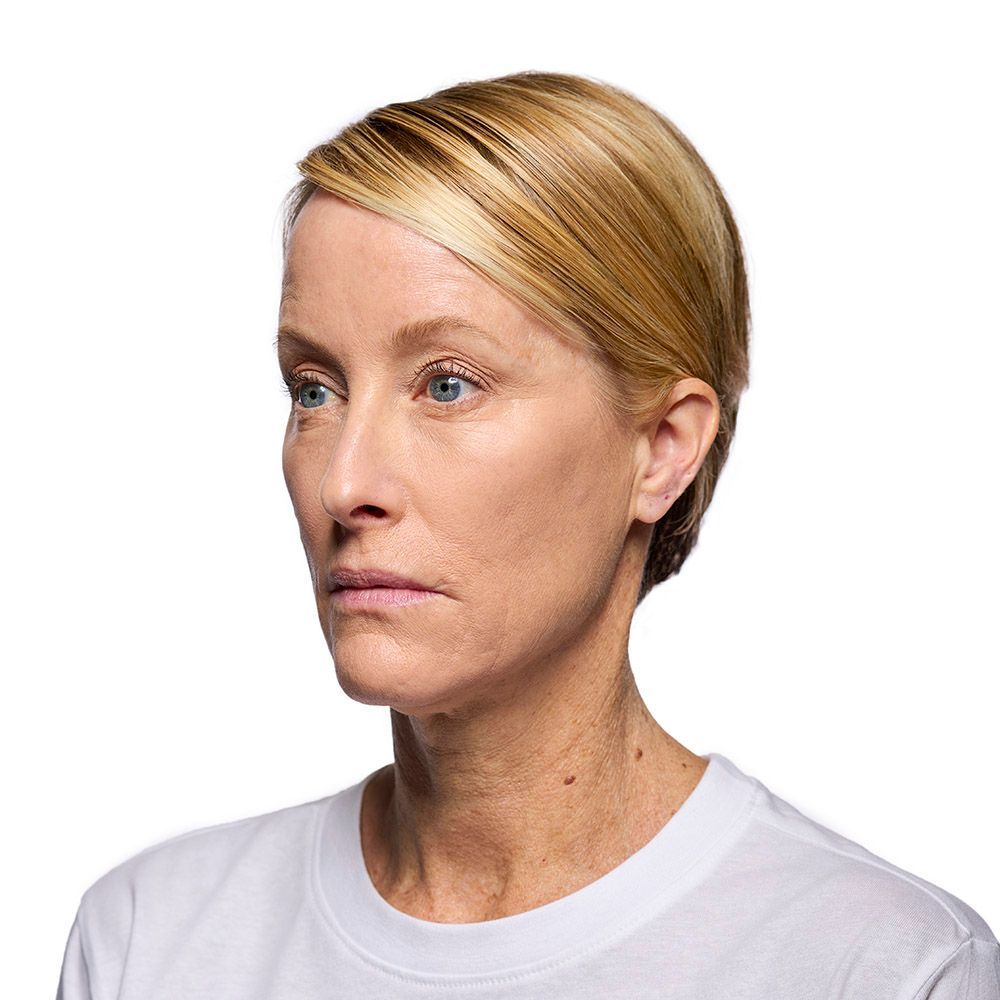 Woman with blonde hair and blue eyes, looking slightly off-camera. She wears a white shirt.