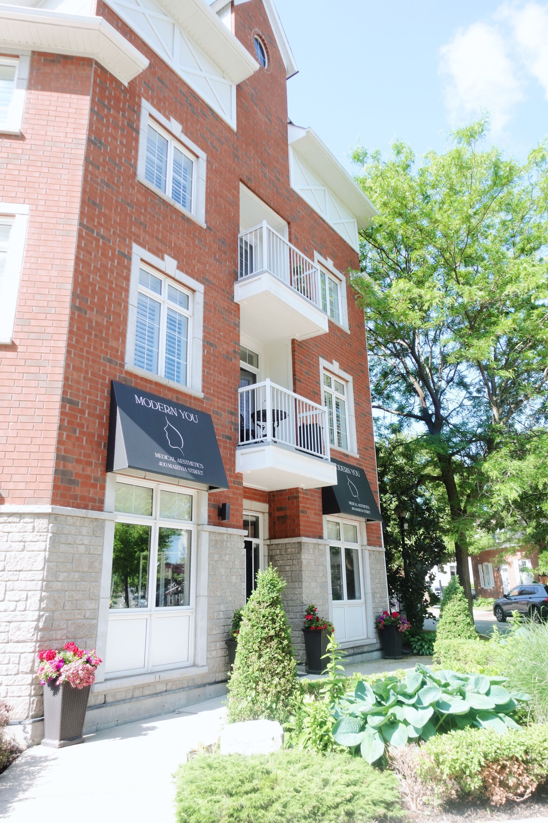 Red brick apartment building with white trim, balconies, and awnings over the entrance.