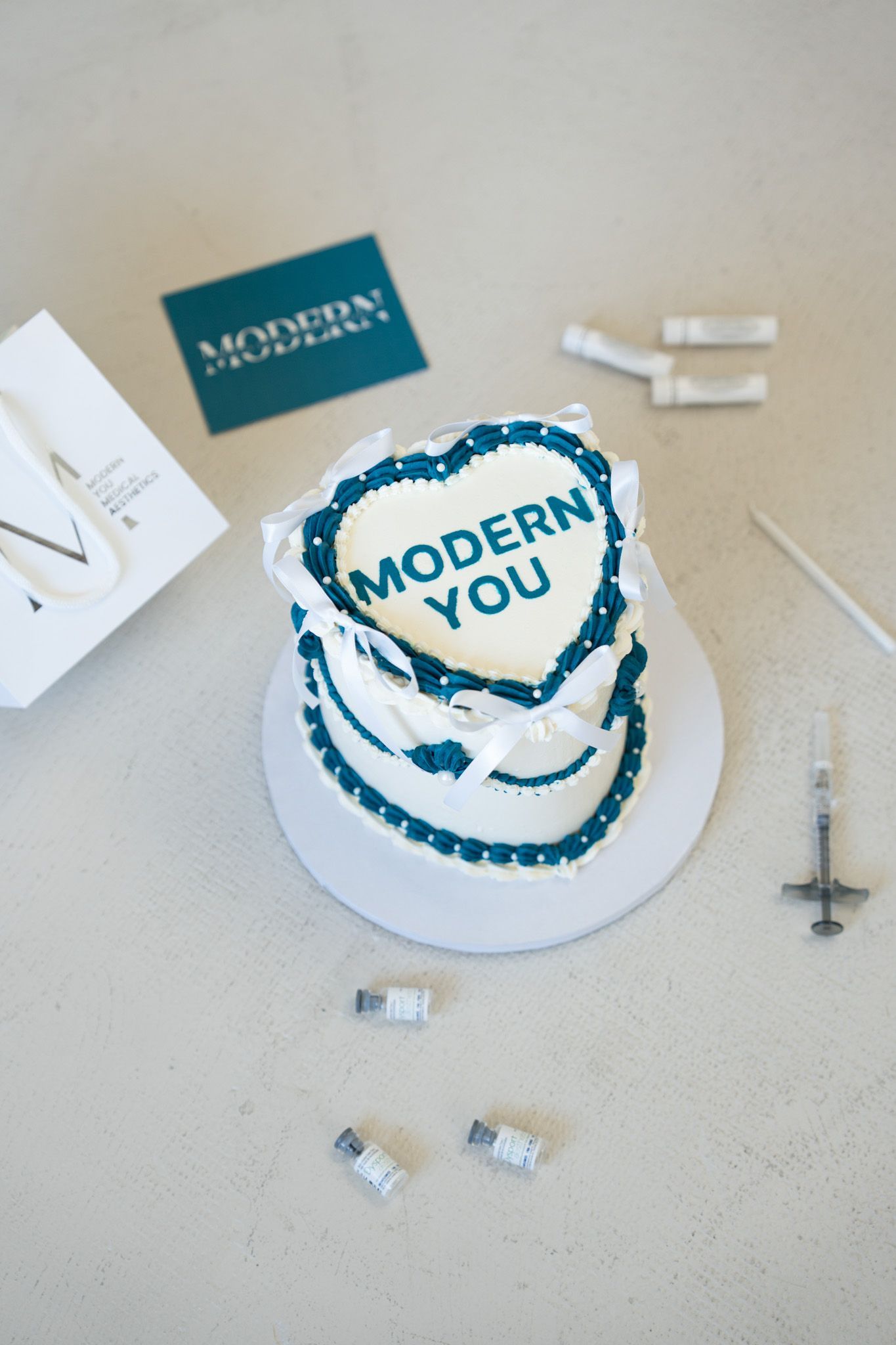 Modern You round cake with blue lettering and white frosting on a table with small tools and box pieces.