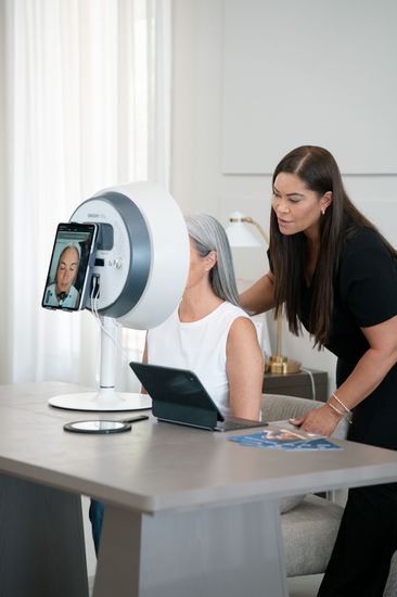 skin anaylsis burlington ontario, nurse in black scrubs helping patient in a machine
