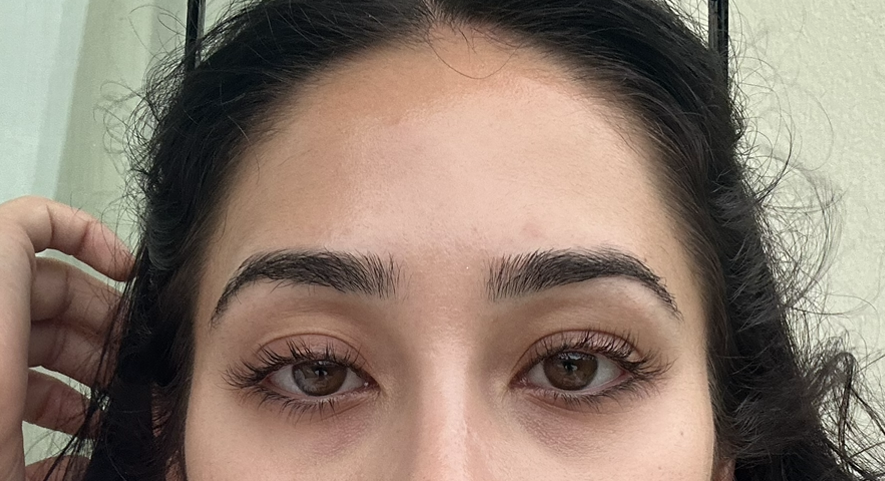 Close-up of a woman's face, looking directly at the viewer. She has dark hair, brown eyes, and visible eyelashes.