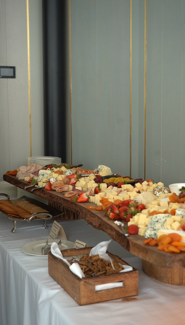 Buffet table with assorted pastries and fruit arranged on wooden trays and a white tablecloth