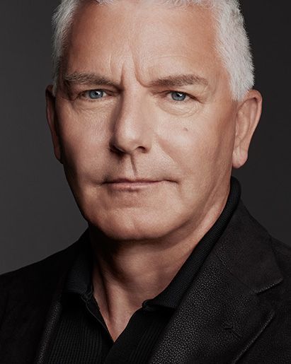 Mature man with short gray hair, wearing a black jacket, looking directly at the camera.