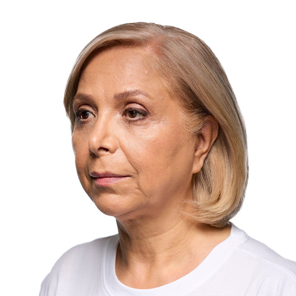 A woman with blonde hair looks to the left. She is wearing a white shirt against a white background.