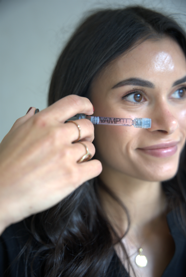 Woman holding a pink VAMP tube to her cheek and smiling softly