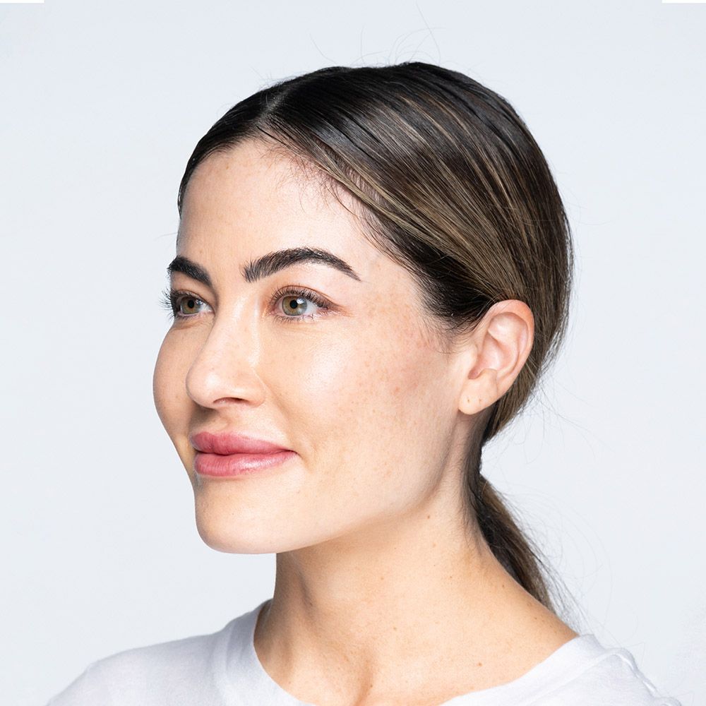 Woman with brown hair pulled back in a ponytail, looking to the left, smiling.