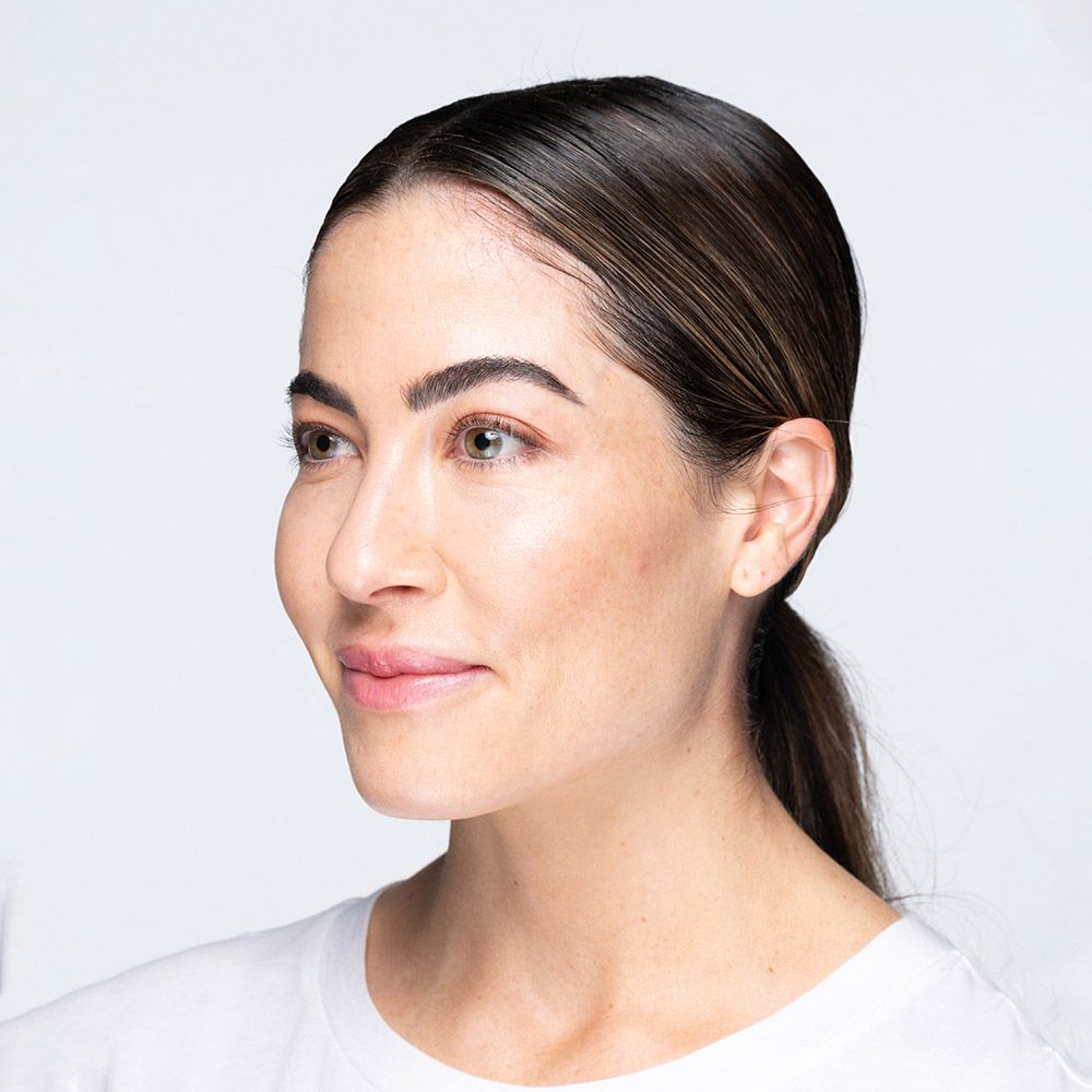Woman with dark hair in a low ponytail, looking to the side, wearing a white shirt.