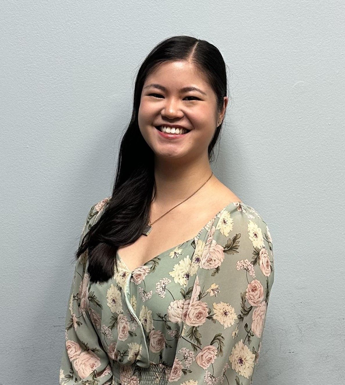 A woman in a floral dress is smiling for the camera.
