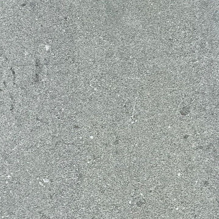 Szara nawierzchnia asfaltowa z małymi kamykami i drobnymi pęknięciami.