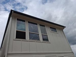 Exterior of a house with white siding and large windows under a cloudy sky