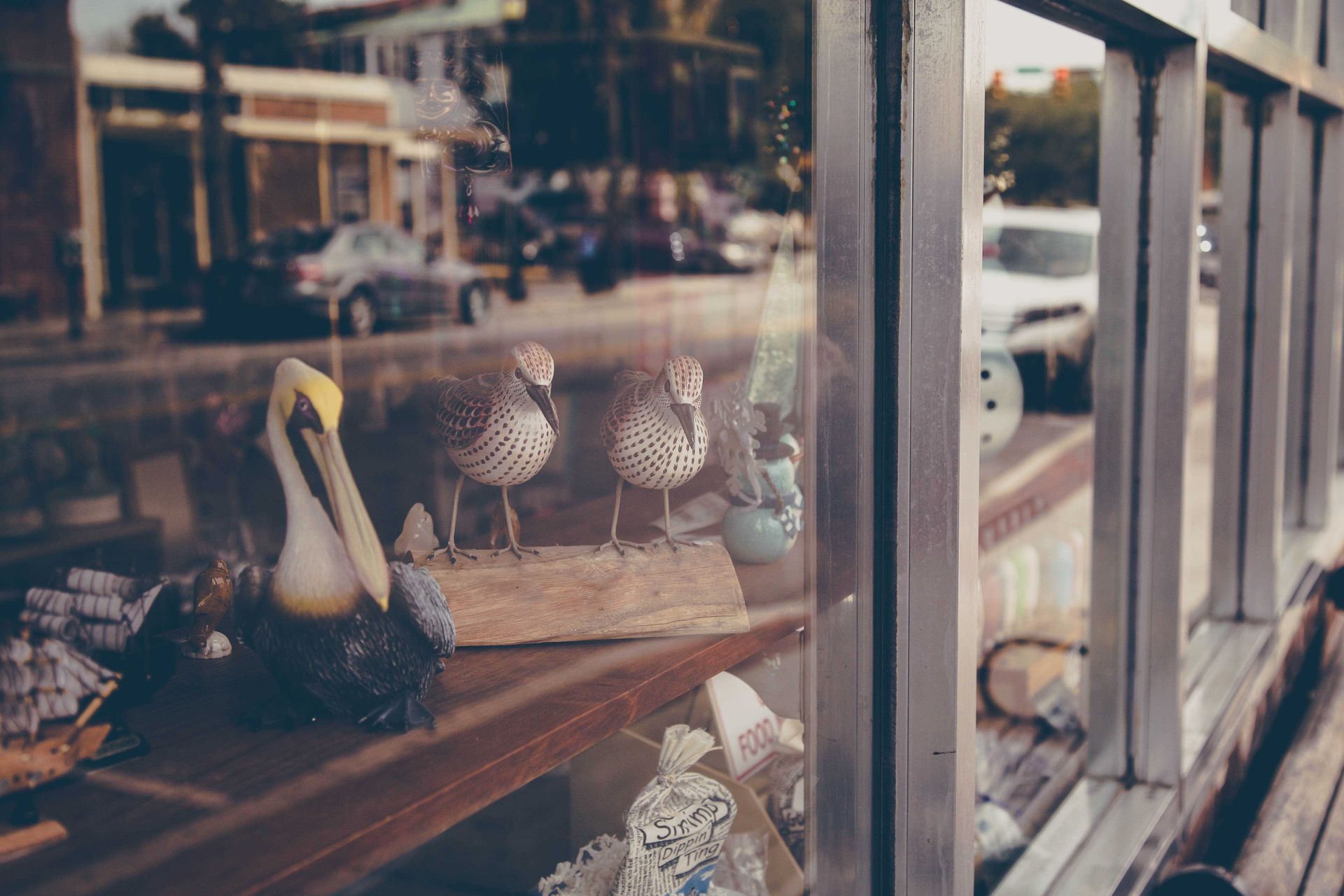 Vitrine d'un magasin présentant des chaussures et des paniers tressés se reflétant dans la rue.