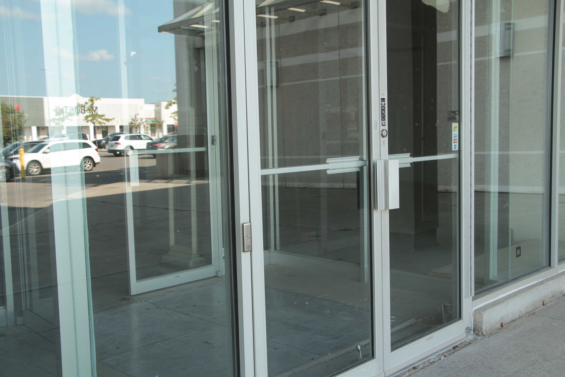 Vitrine vide avec portes à cadre en aluminium et reflets de voitures garées dans la rue