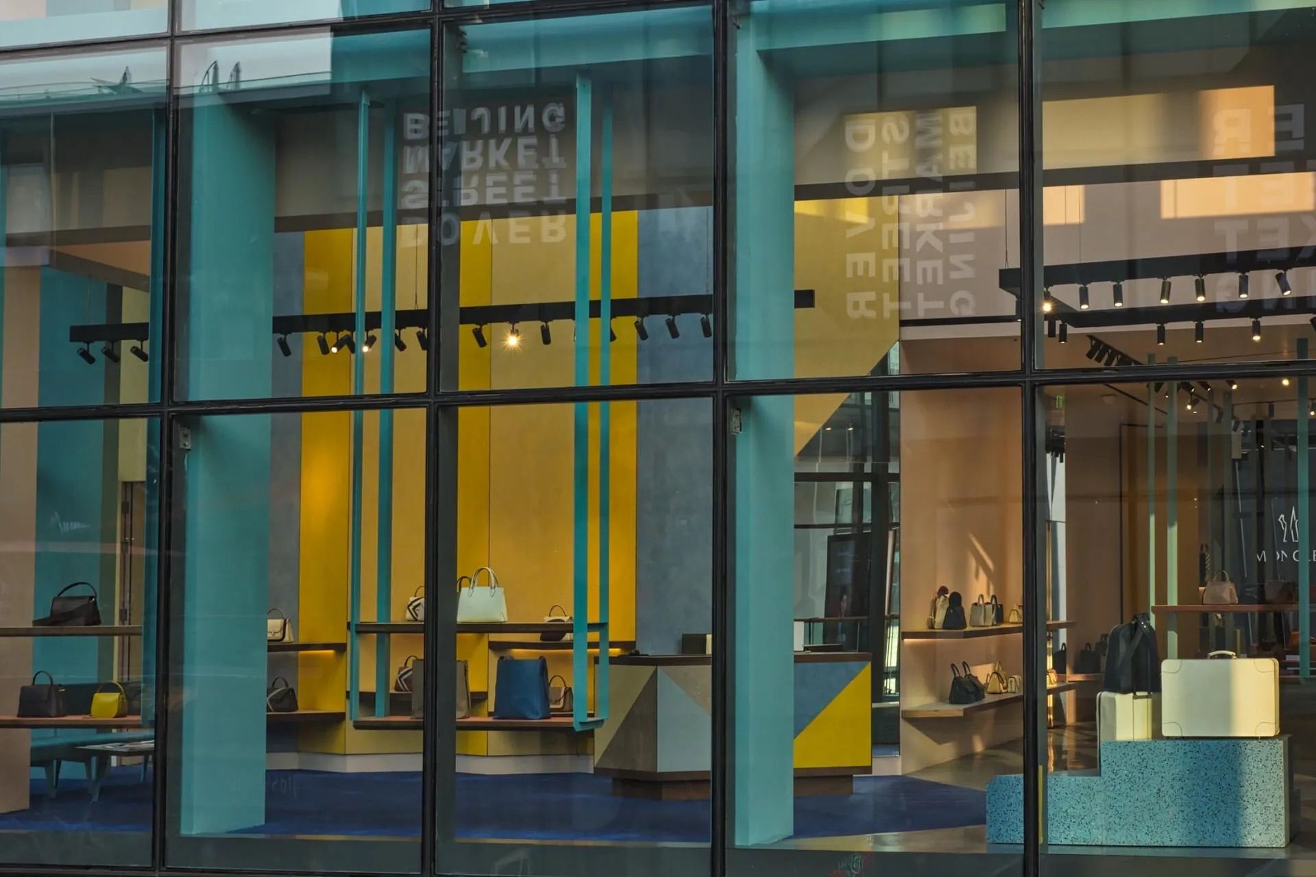 Façade moderne en verre avec encadrement turquoise et espace d'exposition intérieur jaune vif