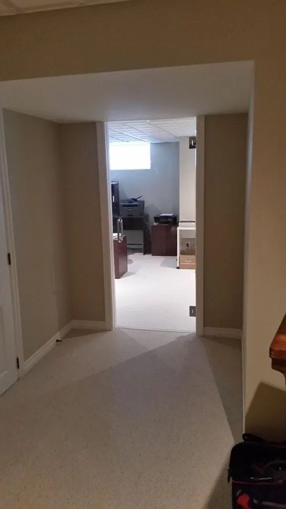 Couloir recouvert de moquette menant à un bureau lumineux avec un bureau et une chaise