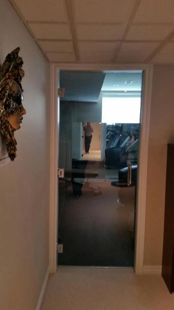 Porte vitrée d'un bureau dans un couloir, reflétant une salle de conférence avec des chaises et une table à l'intérieur.