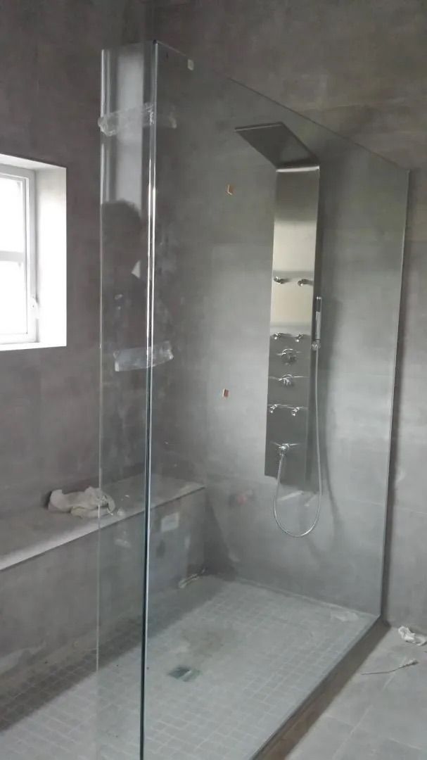 Salle de bains moderne avec douche à l'italienne en verre et murs carrelés gris