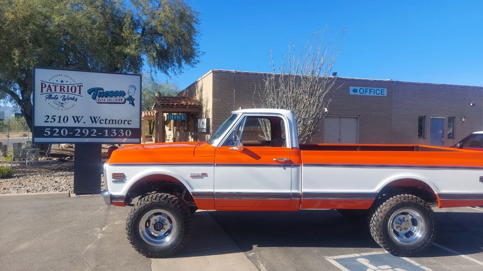 a white and orange classic truck parked in front of a sign