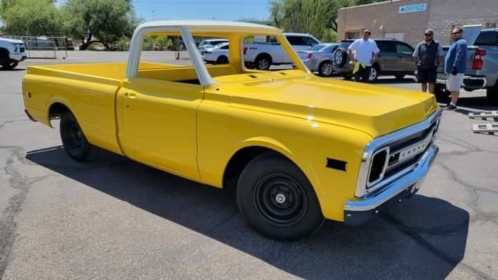 A yellow pickup truck is parked in a parking lot.