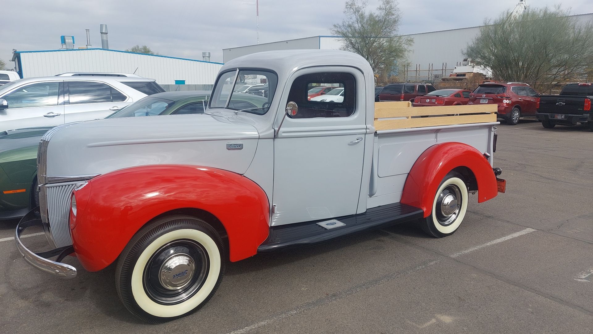 a red and grey classic truck is parked in a parking lot