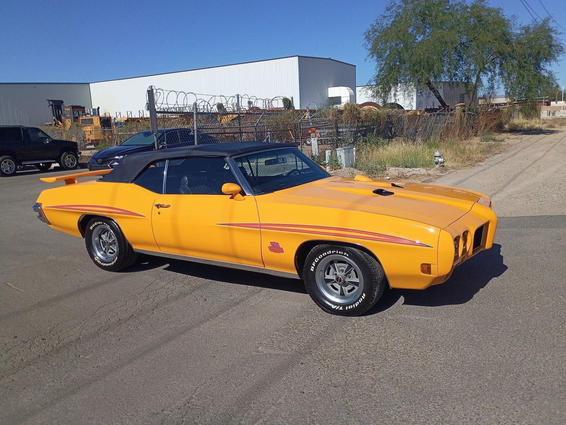 Orange classic muscle car parked on a roadside in an industrial area
