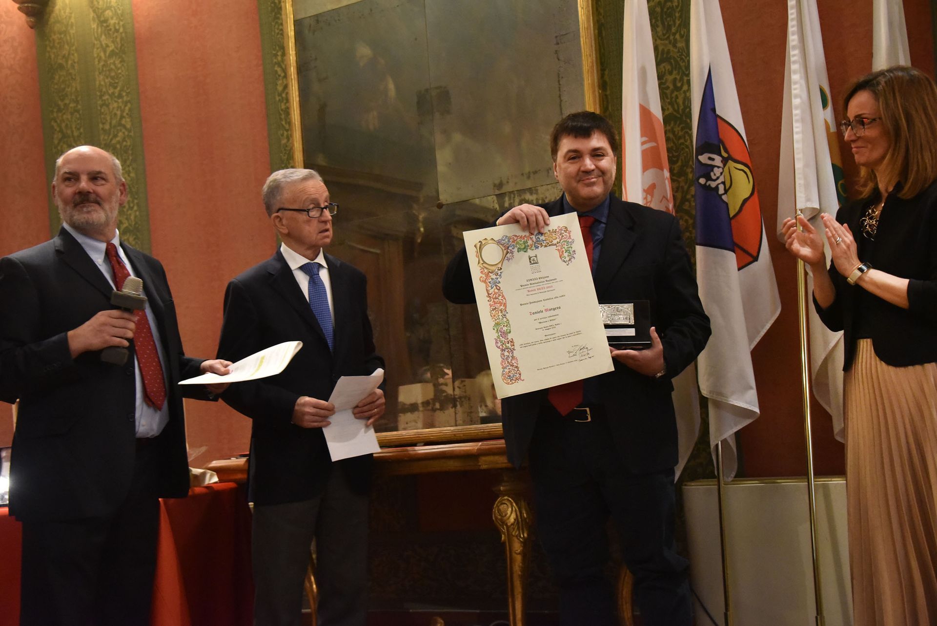 Un uomo tiene in mano un certificato di fronte a un gruppo di persone.
