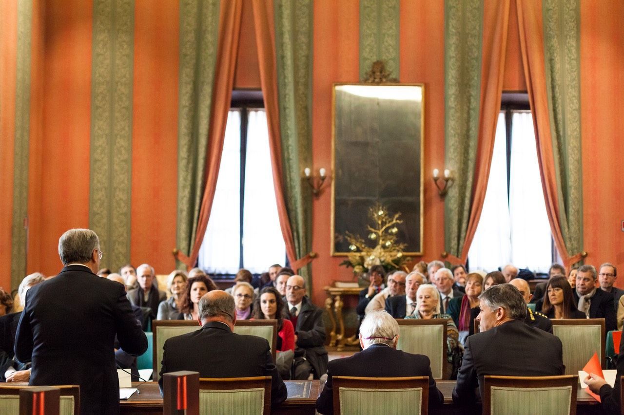 Un uomo tiene un discorso a un gruppo di persone in una grande stanza.