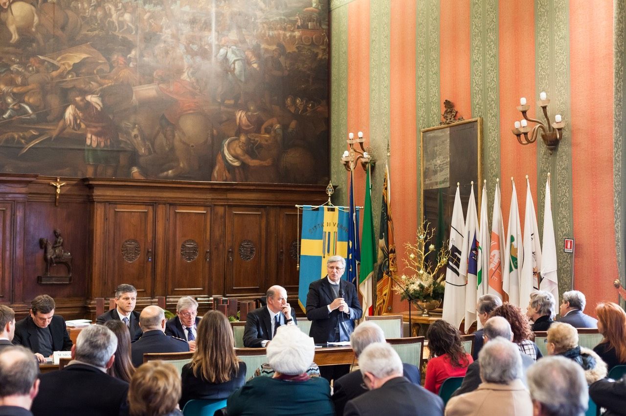 Un uomo tiene un discorso davanti a una folla di persone in una grande stanza.