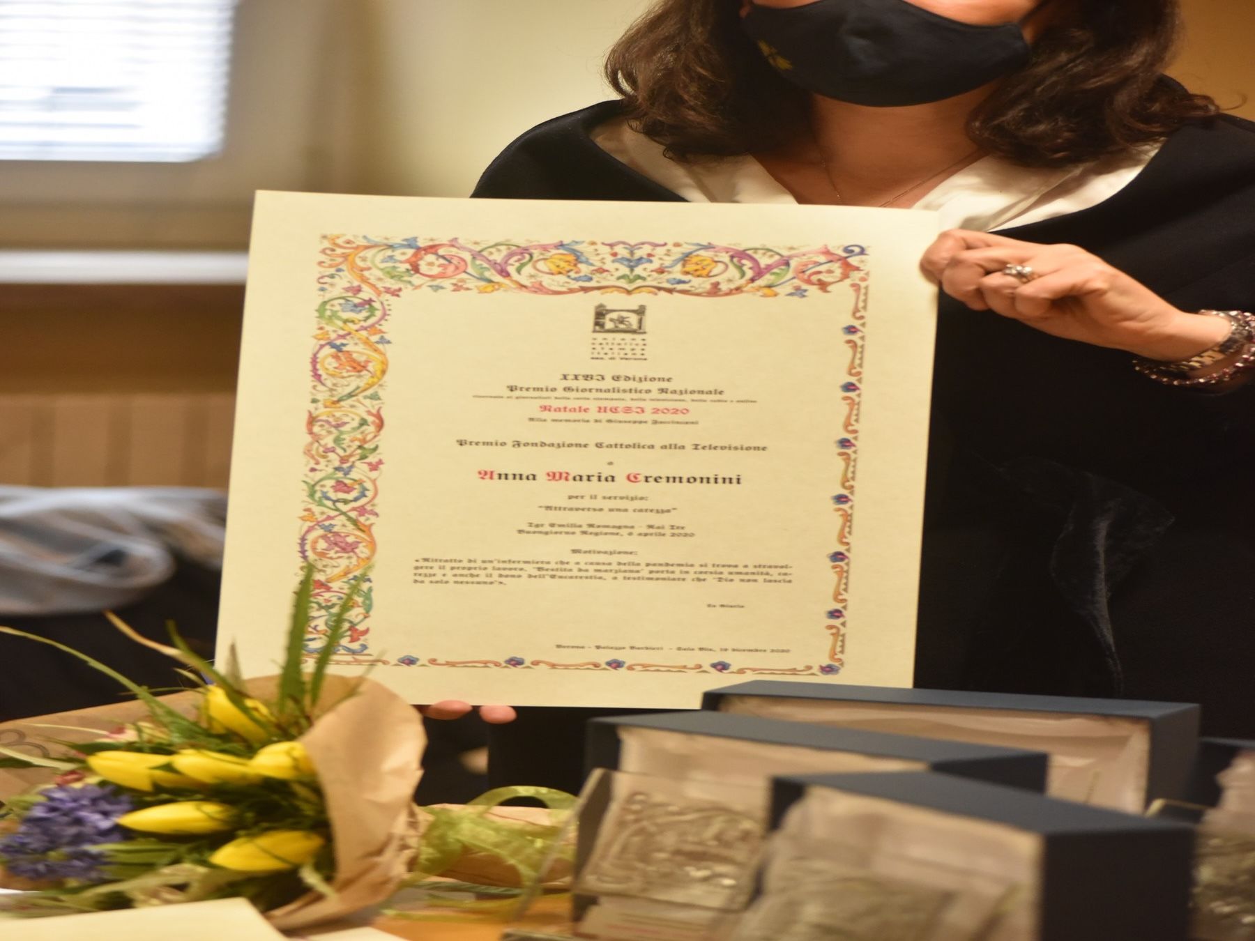 Una donna che indossa una maschera nera tiene in mano un certificato