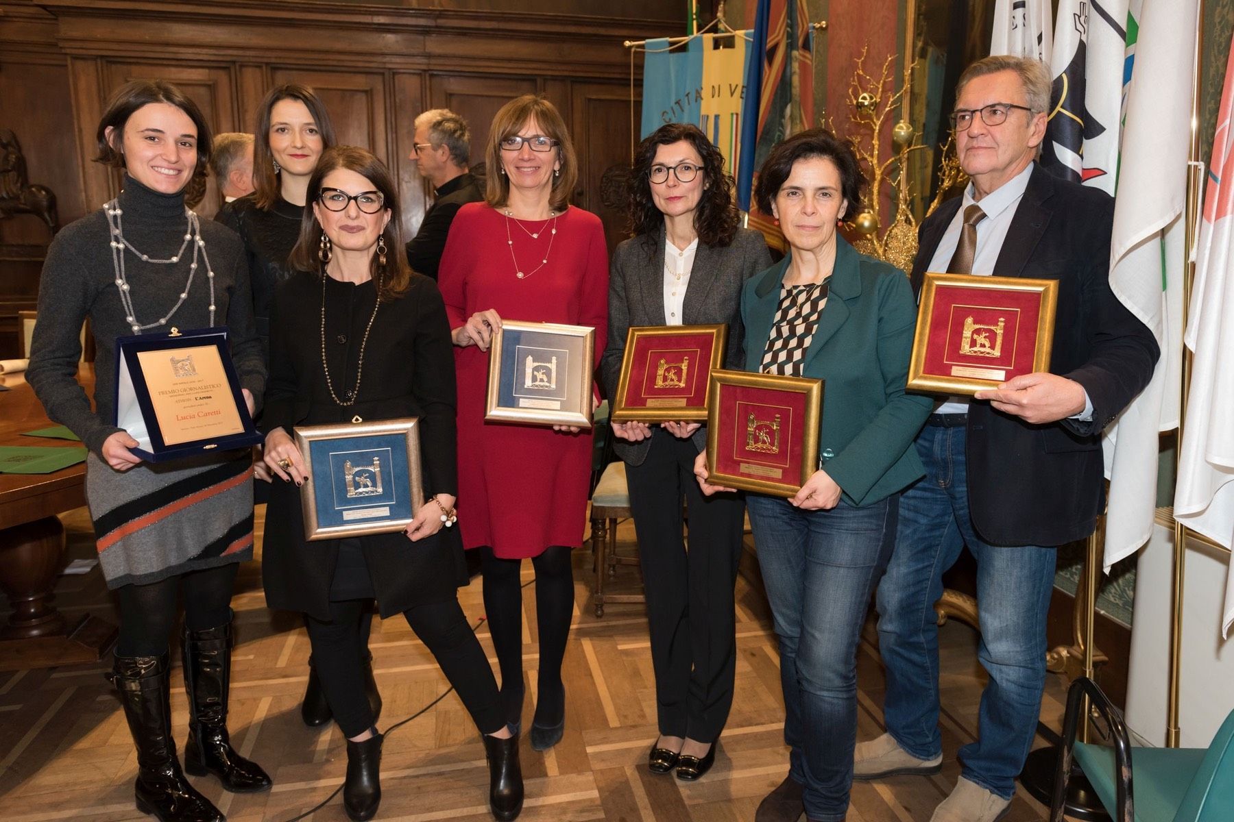Un gruppo di persone è in piedi uno accanto all'altro con in mano delle targhe.