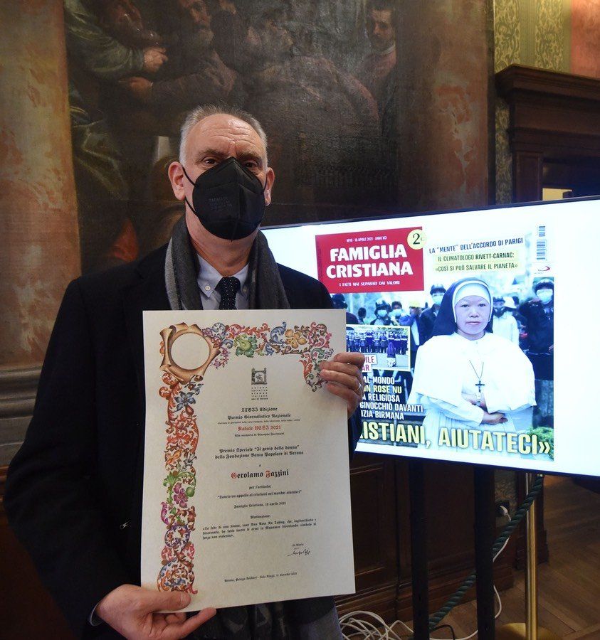 Davanti a uno schermo un uomo mascherato tiene in mano un certificato con la scritta Famiglia cristiana