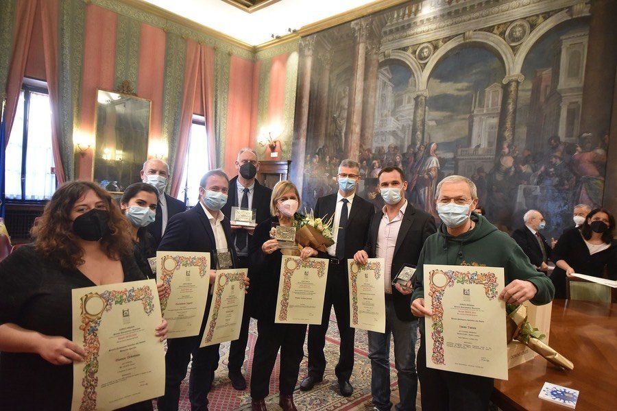 Un gruppo di persone che indossano maschere per il viso tengono in mano certificati in una stanza.