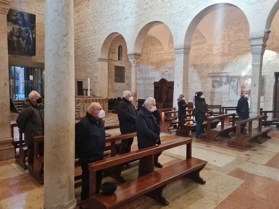 Un gruppo di uomini che indossano maschere per il viso sono seduti in una chiesa.