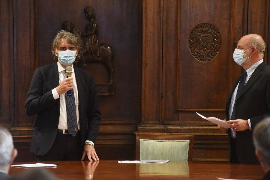 Due uomini che indossano maschere per il viso sono in piedi uno accanto all'altro a un tavolo.