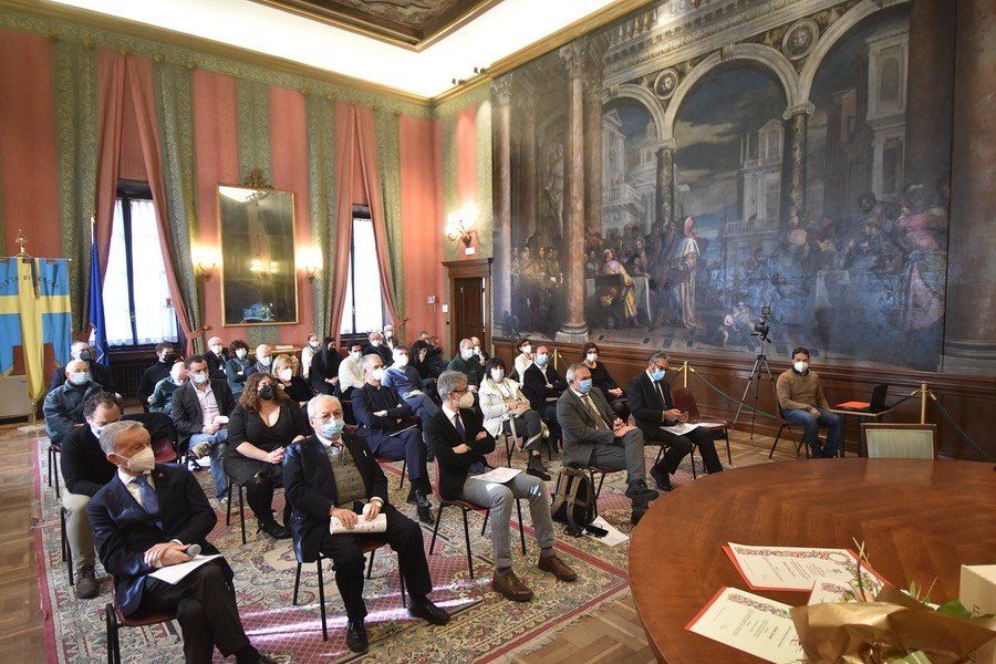 Un gruppo di persone è seduto sulle sedie in una grande stanza.