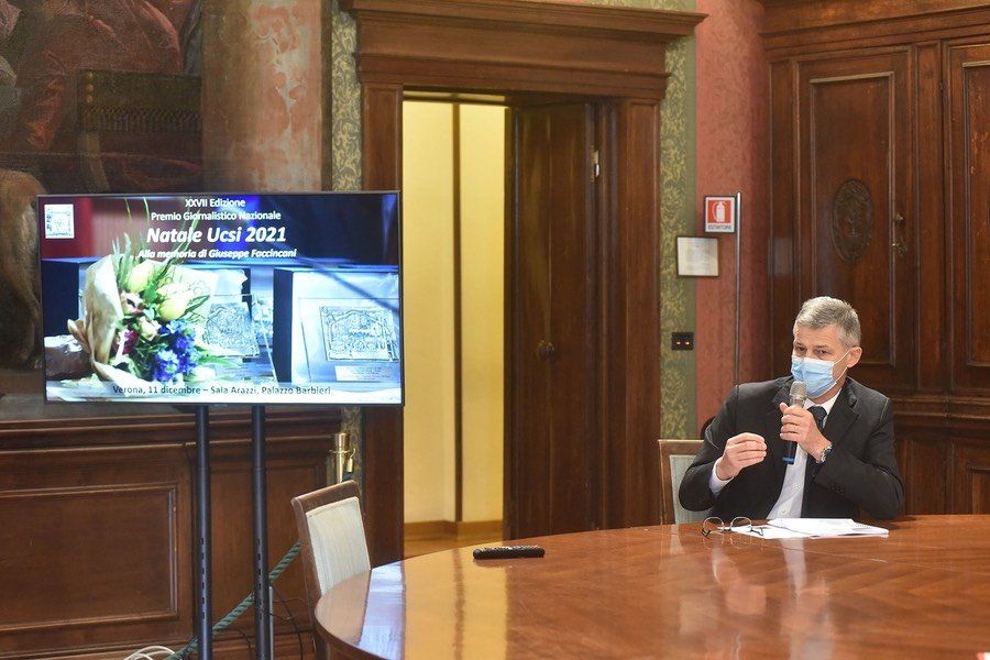 Un uomo che indossa una maschera è seduto a un tavolo davanti a un televisore.