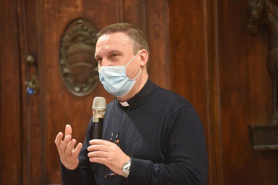 Un uomo che indossa una maschera tiene in mano un microfono e parla al suo interno.