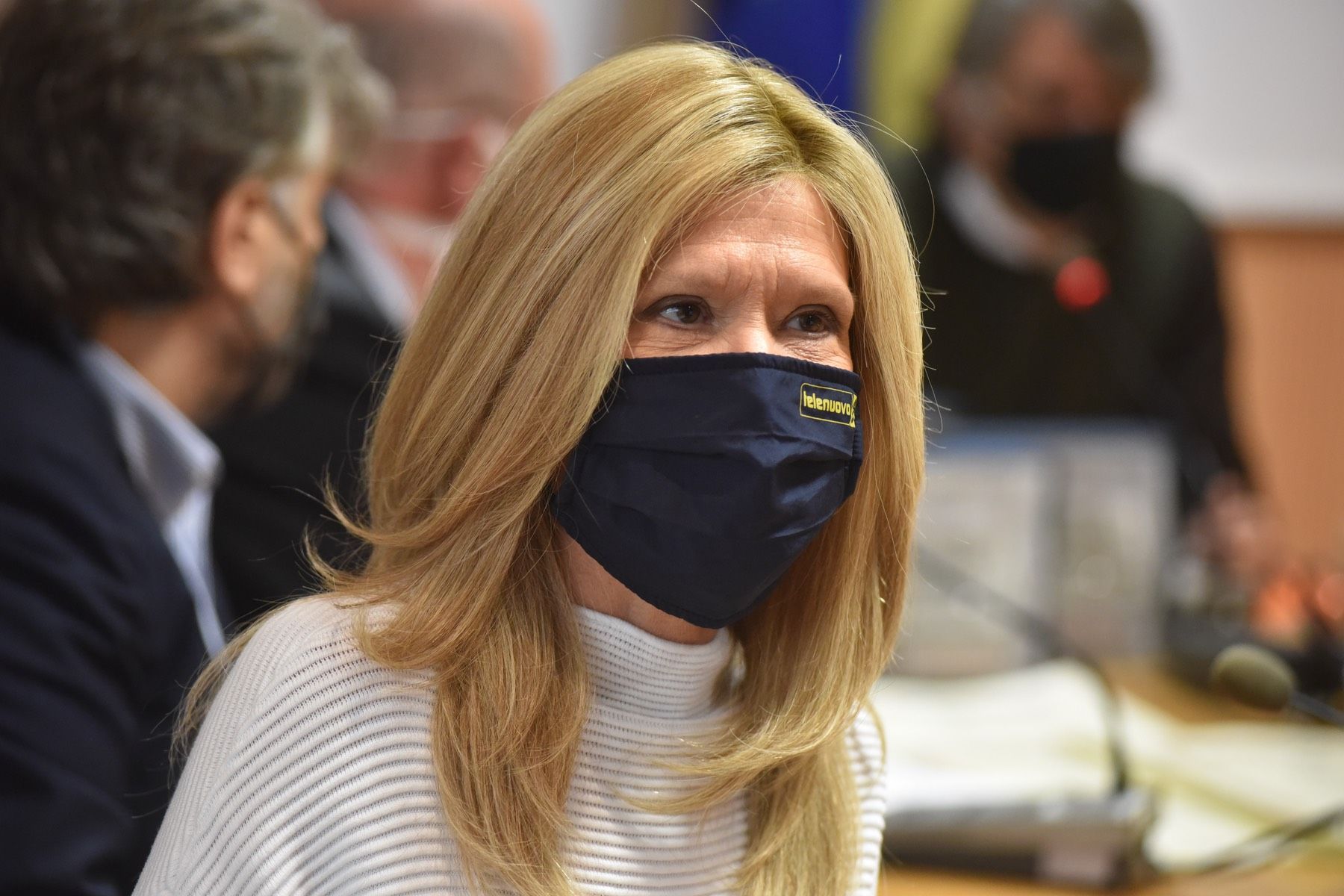 Una donna che indossa una maschera è seduta a un tavolo.
