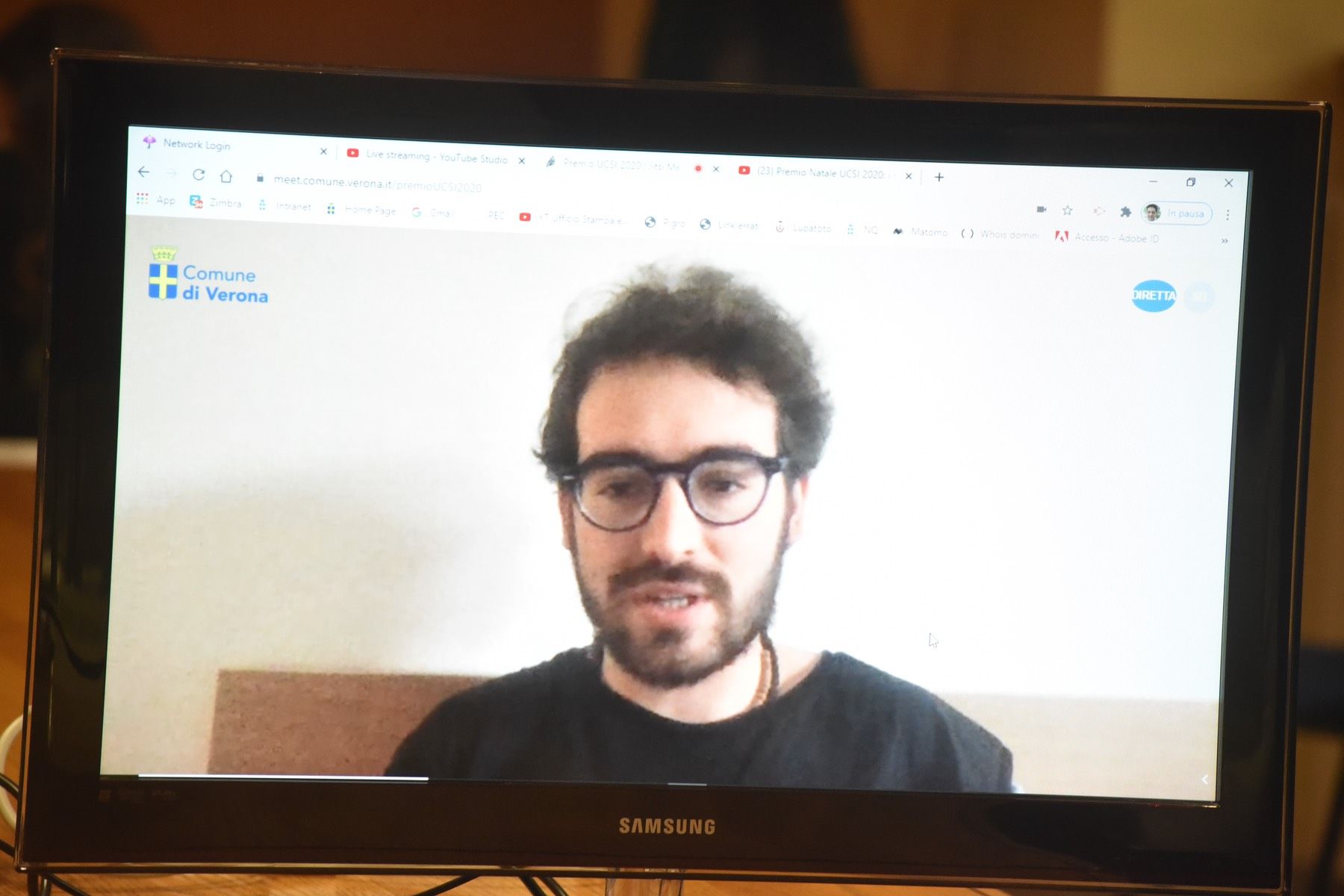 Un uomo con gli occhiali è seduto davanti a un televisore Samsung.