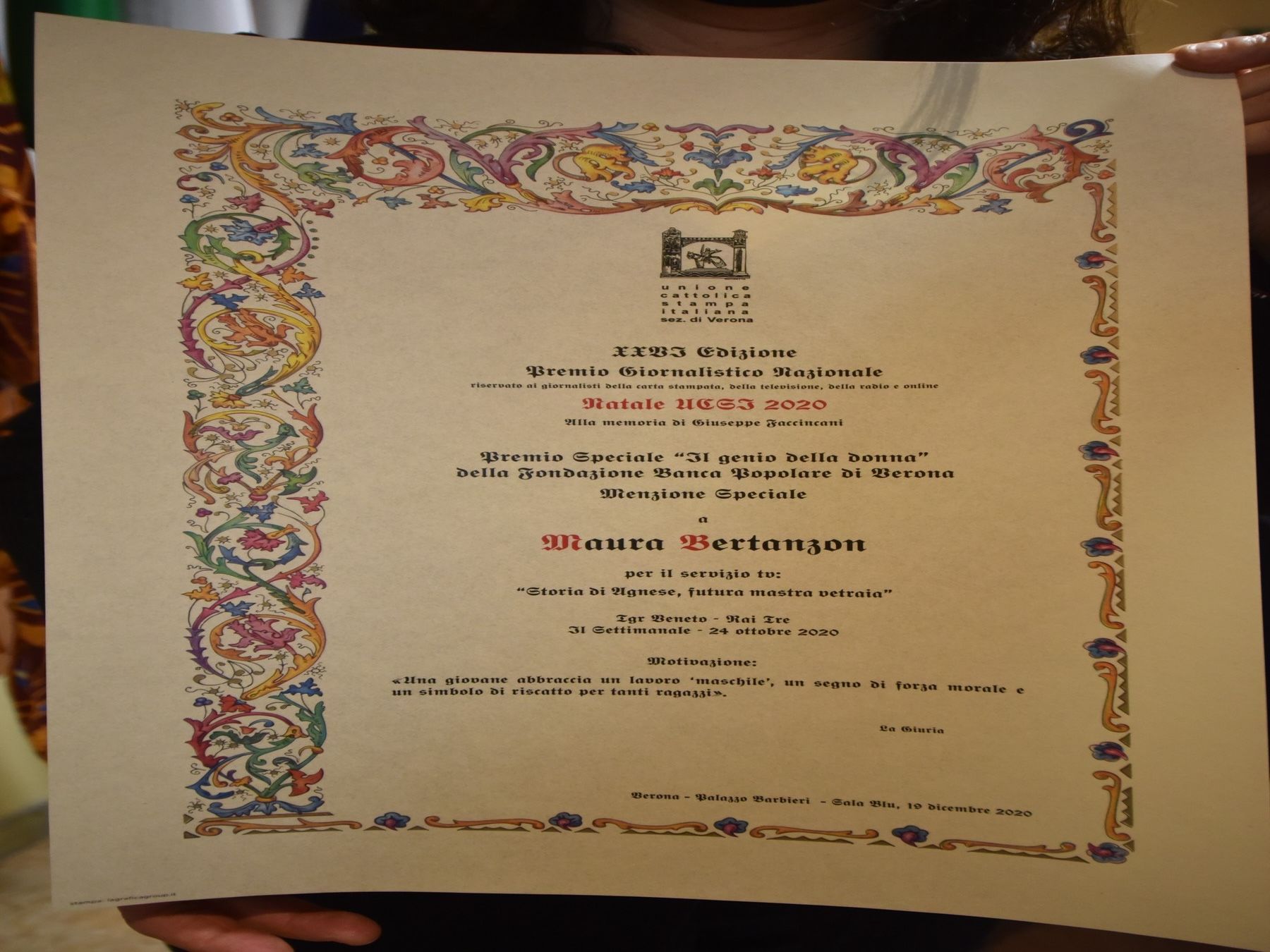 Una donna tiene in mano un pezzo di carta con un bordo colorato su cui è scritto