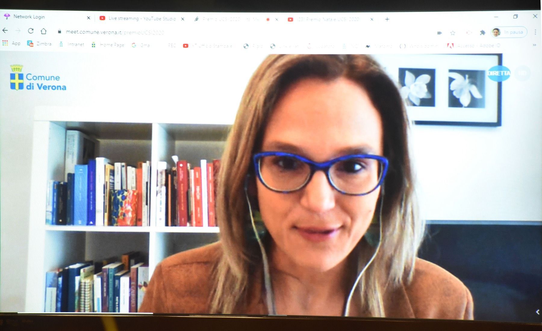 Una donna con gli occhiali sta parlando durante una videochiamata sullo schermo di un computer.