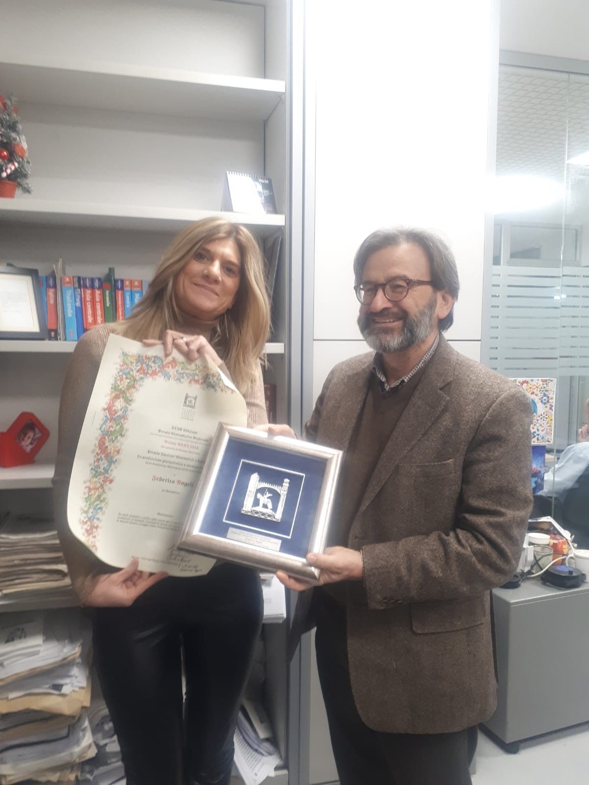 Un uomo e una donna tengono in mano un certificato incorniciato.