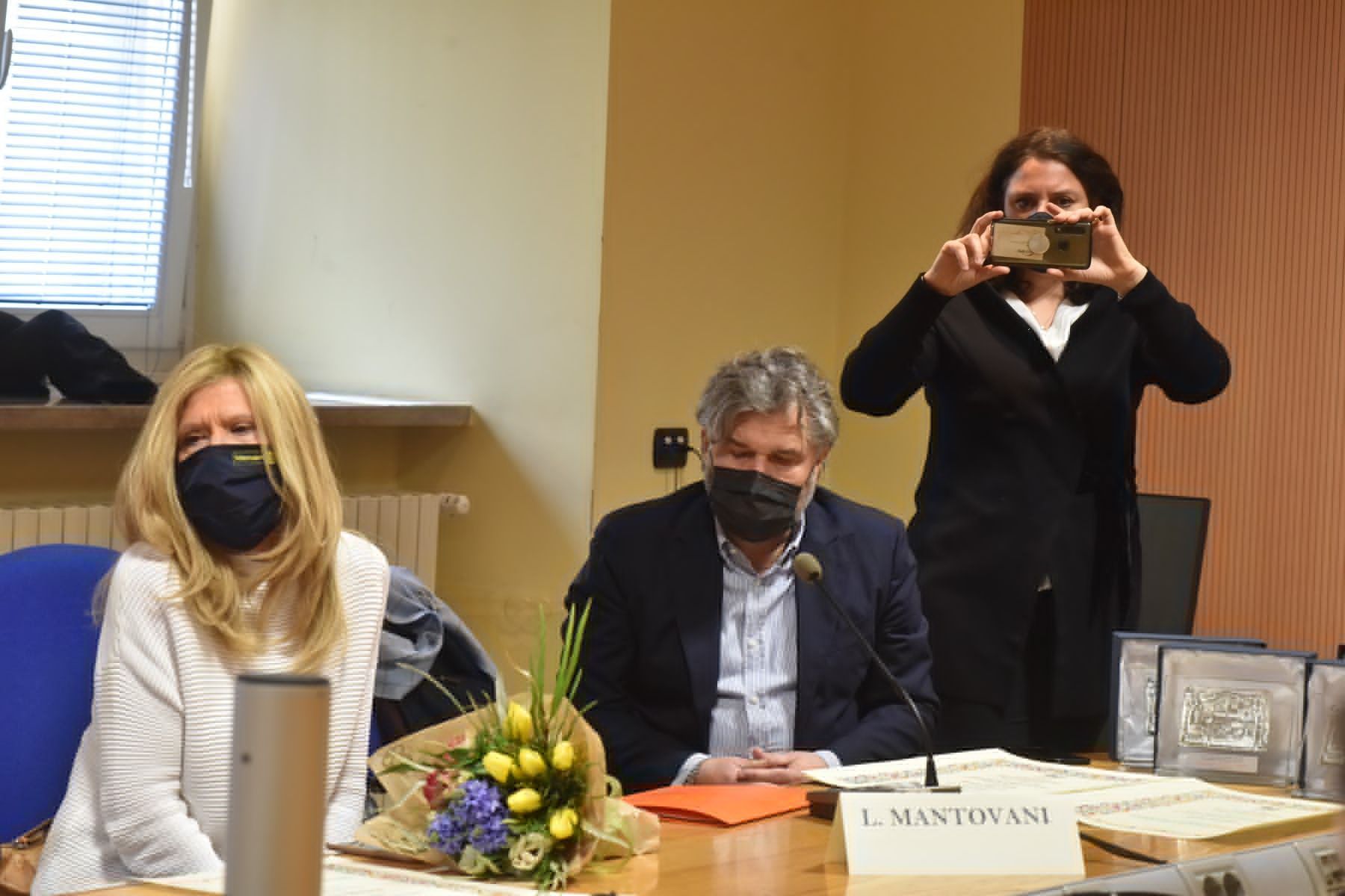 Una donna sta scattando una foto di un uomo e una donna seduti a un tavolo.