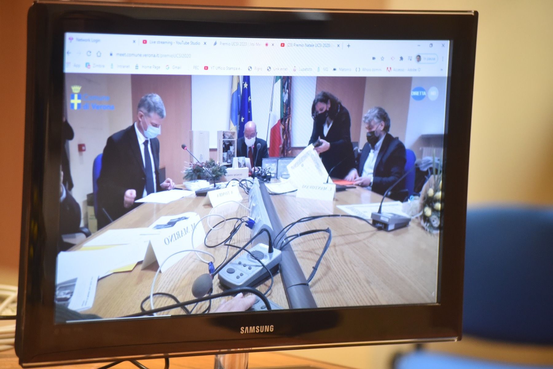 Un monitor Samsung mostra un gruppo di persone sedute attorno a un tavolo