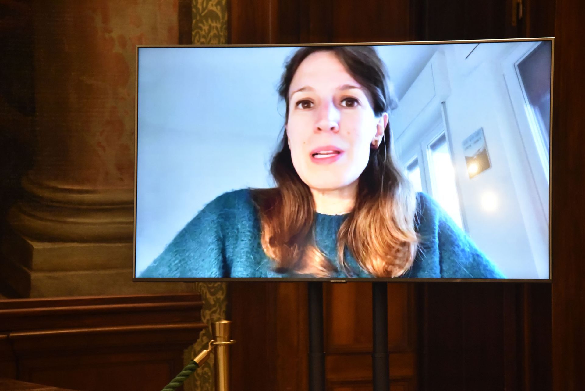 Una donna è seduta davanti a un grande televisore a schermo piatto.