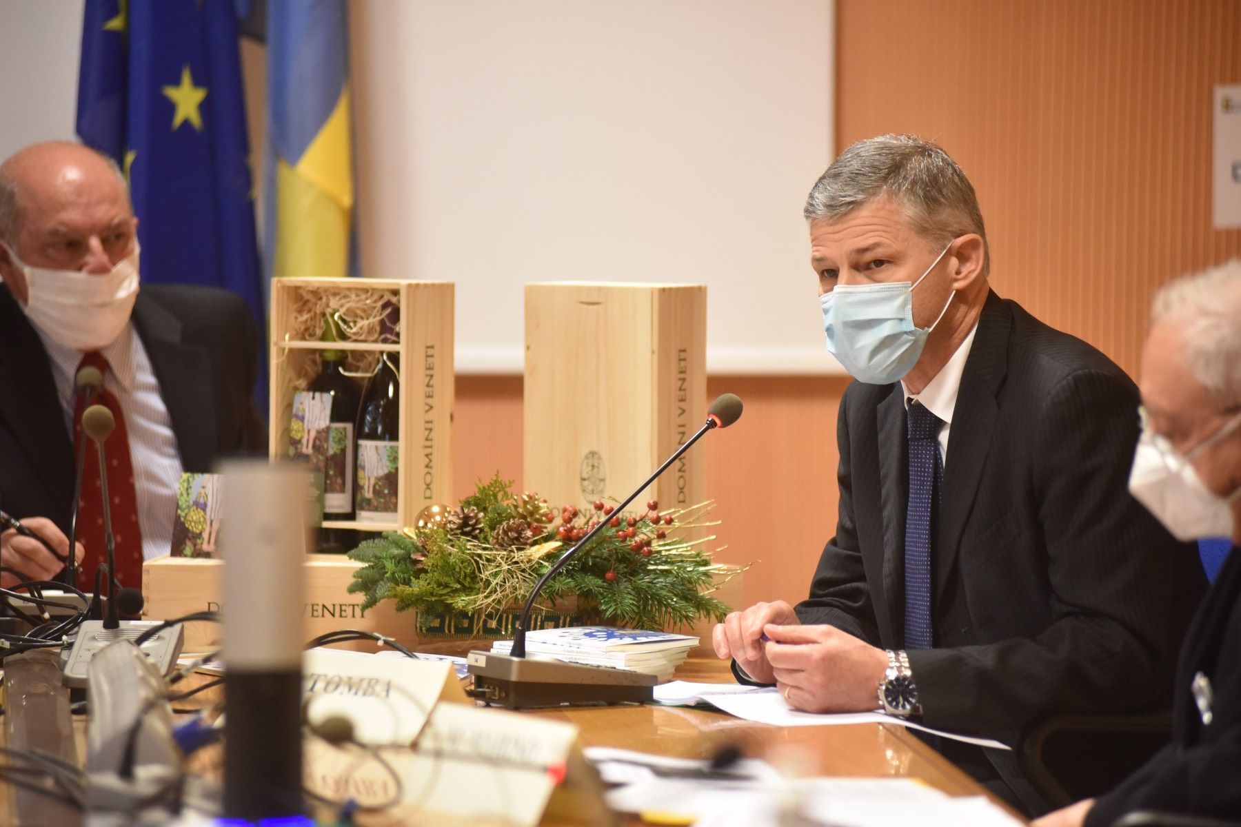 Un gruppo di uomini che indossano maschere per il viso sono seduti a un tavolo.