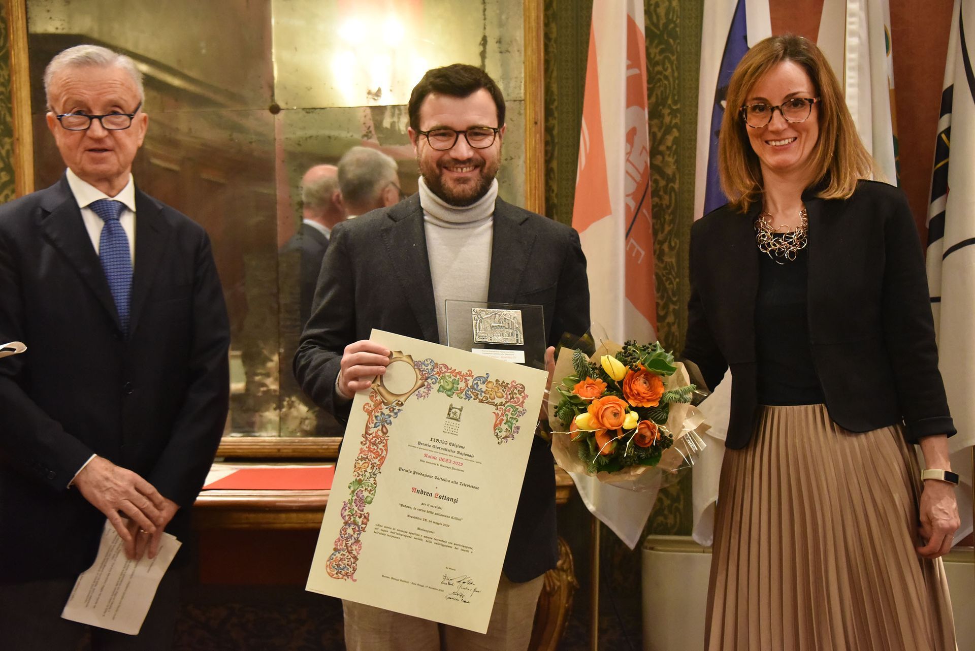 Un uomo tiene in mano un certificato e una donna tiene in mano un mazzo di fiori.