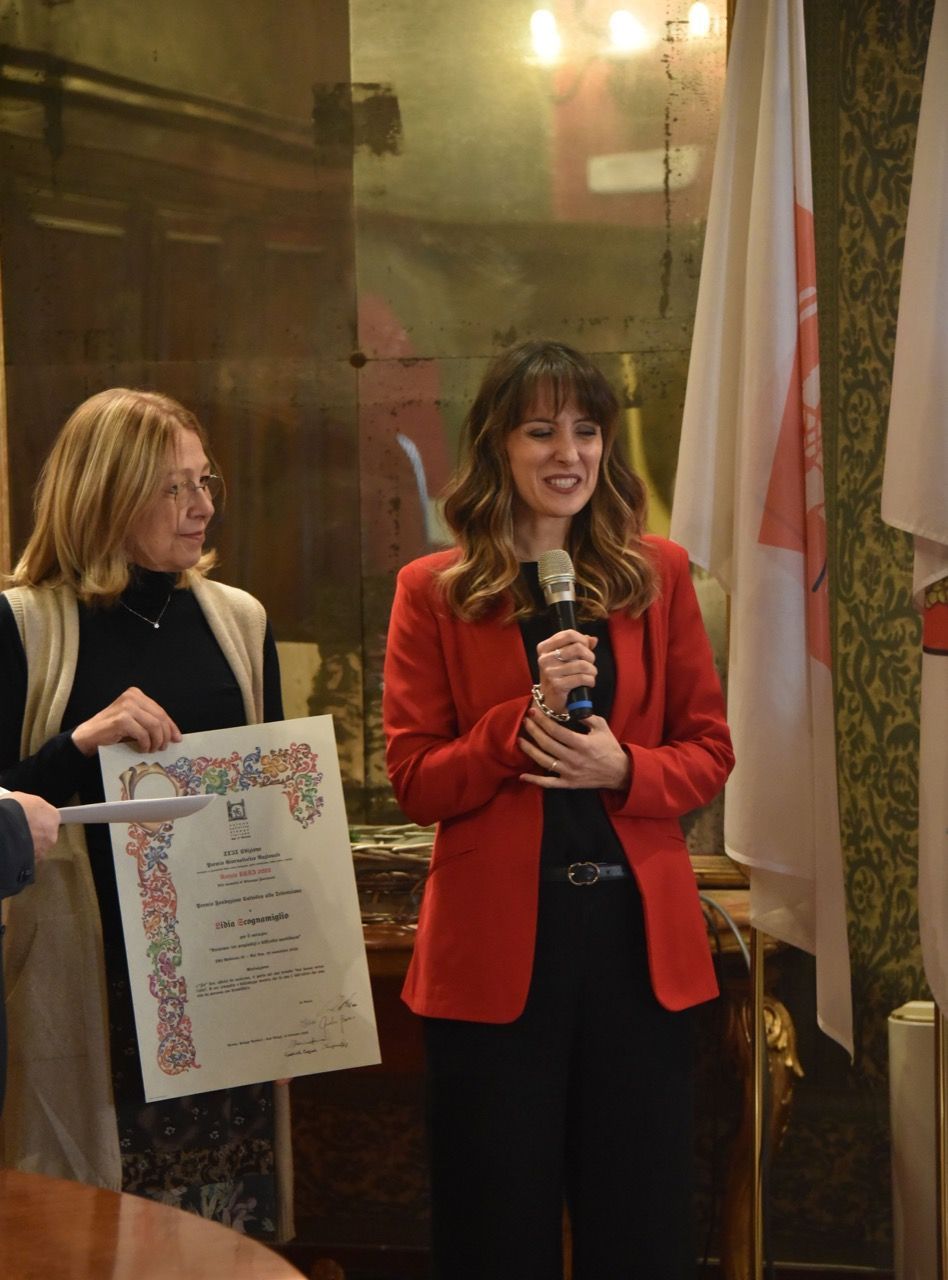 Una donna con una giacca rossa parla al microfono